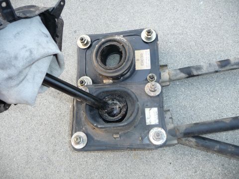 1993 Mazda MX-3 - Car gear shifter assembly with rubber boots and metal rods, one rod covered by a cloth.