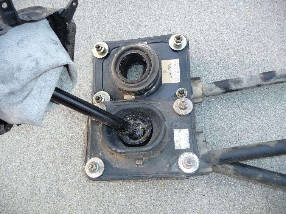 Car gear shifter assembly with rubber boots and metal rods, one rod covered by a cloth