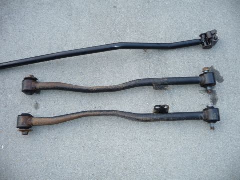 1993 Mazda MX-3 - Three automotive suspension control arms are shown on a concrete surface.