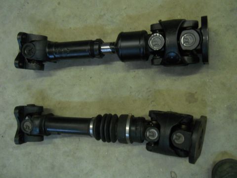 1992 Ford Bronco - Two automotive driveshafts are shown side-by-side on a concrete surface.