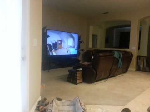 1994 Ford Bronco - A living room scene features a large television displaying an interior view, alongside a brown leather recliner and a dog bed.