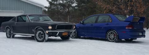 1968 Ford Mustang - Two cars, a classic Mustang and a modern Lancer Evolution, sit side-by-side in a snowy environment.