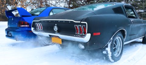 1968 Ford Mustang - Two cars drive through the snow, kicking up a cloud of white powder.