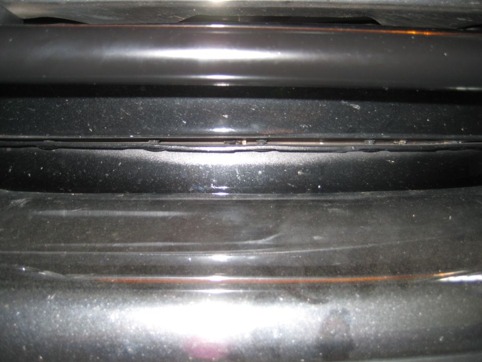 Close-up of black car grille with horizontal bars and a thin gap between them