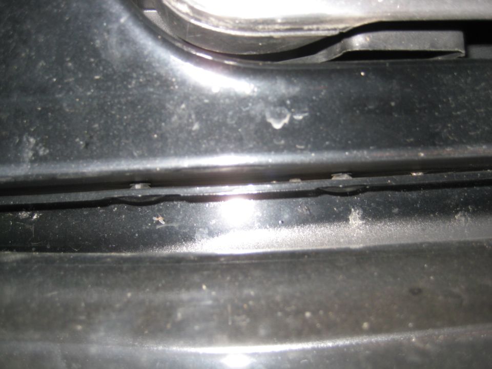 Close-up of dark body panel seam with black plastic trim, dust and flash glare on a 1995 Ford Bronco