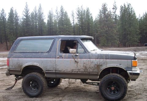 1990 Ford Bronco - This lifted and muddy 1990 Ford Bronco is seen from the side in an outdoor, off-road setting.