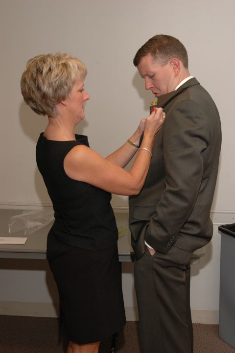 1985 Ford Crown Victoria LTD - A woman fastens a boutonniere to a man's suit jacket, likely for a formal event.