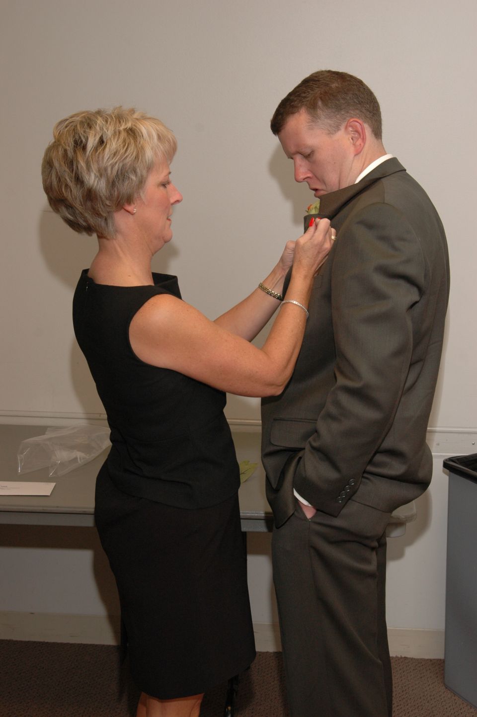 Woman pinning boutonniere on man's suit lapel