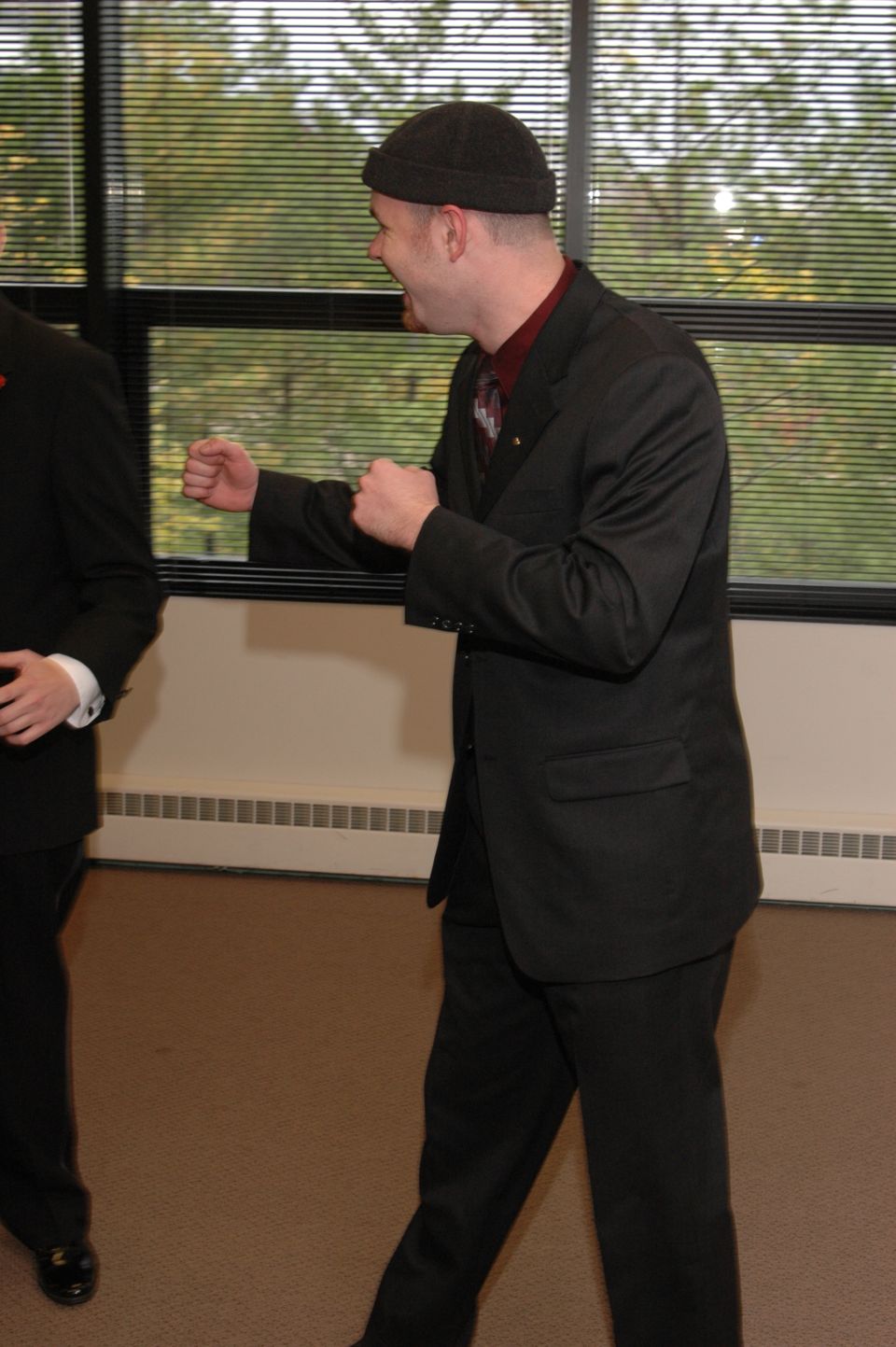 Man in suit and beanie playfully posing with fists up