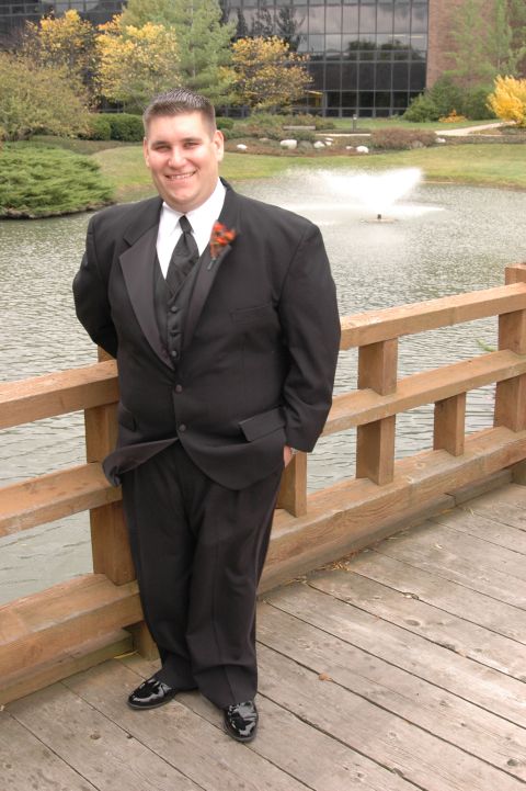 1985 Ford Crown Victoria LTD - A man in a tuxedo poses for a photo on a wooden bridge with a pond and building in the background.