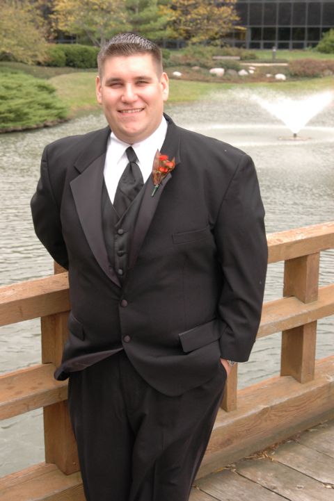 1985 Ford Crown Victoria LTD - A man dressed in a tuxedo poses for a photo near a water feature.
