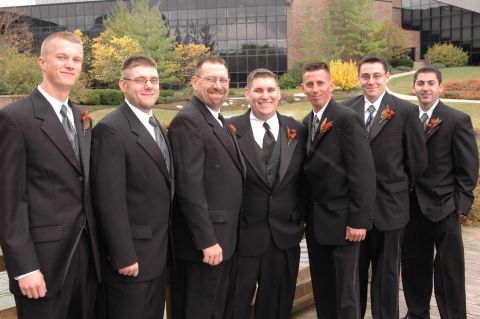 1985 Ford Crown Victoria LTD - A wedding party poses for a photo in front of a modern building, with trees showing autumn colors.