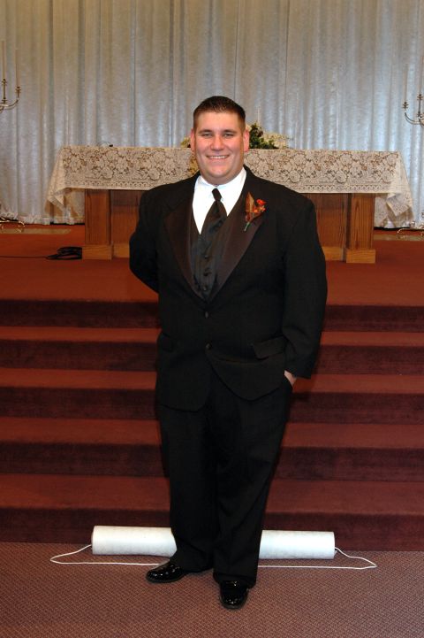 1985 Ford Crown Victoria LTD - A groom poses for a photo in front of the altar at a wedding ceremony.