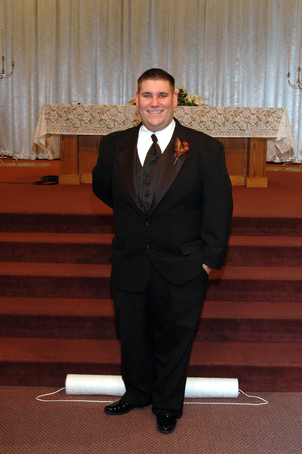 Man in a black tuxedo stands in front of a church altar