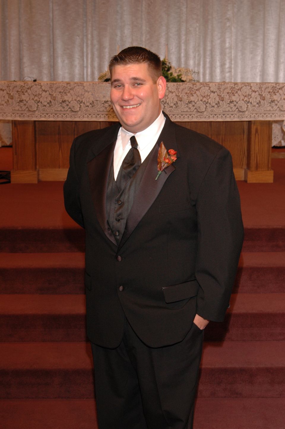 man in tuxedo with boutonniere standing in front of altar