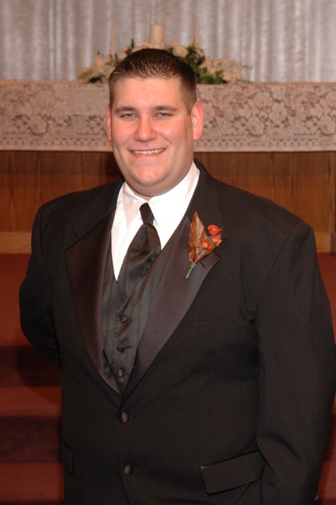 1985 Ford Crown Victoria LTD - A groom smiles for a photo in front of an altar.