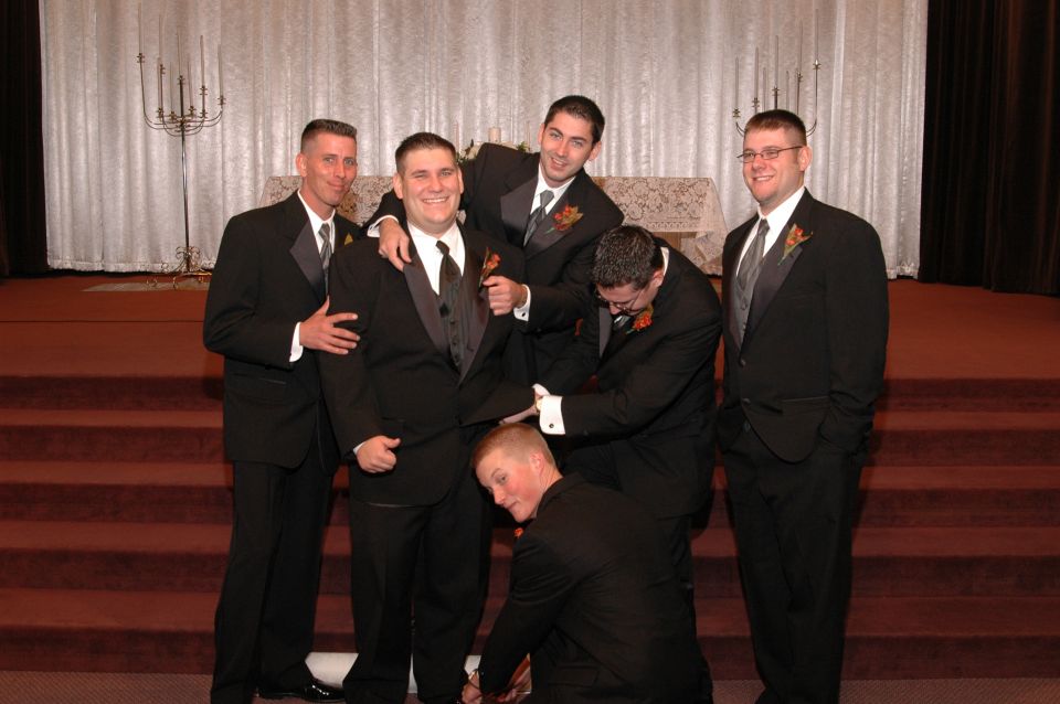 Groom and groomsmen in tuxedos posing for a photo on church steps
