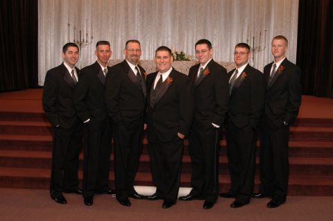 1985 Ford Crown Victoria LTD - Seven men in formal attire pose for a photograph in what appears to be a wedding or formal event setting.
