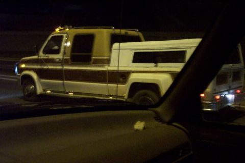 1992 Ford Bronco - Custom van conversion with camper shell and extended cab, viewed from a car at night.