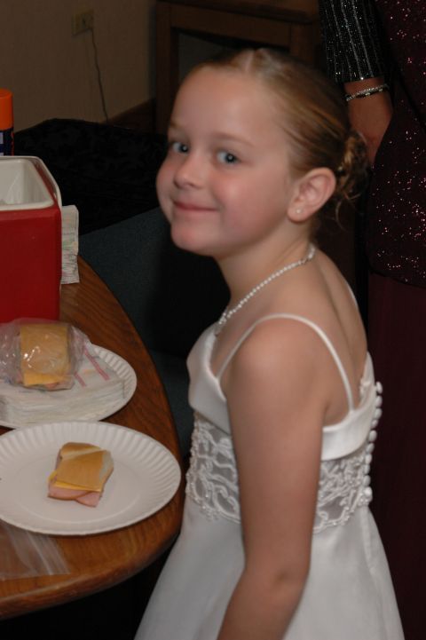 1985 Ford Crown Victoria LTD - A young girl in a formal white dress smiles while sitting at a table with sandwiches.