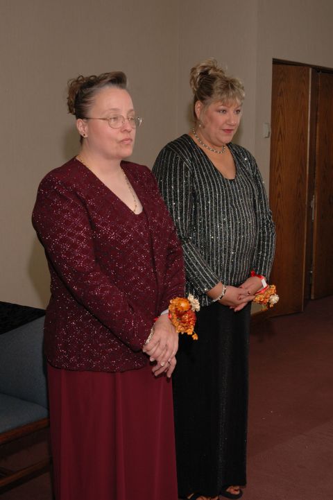 1985 Ford Crown Victoria LTD - Two women in formal dresses and corsages are standing together.