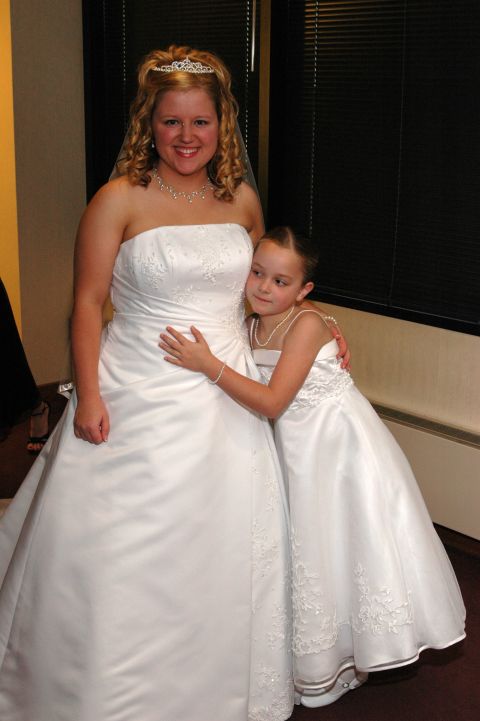 1985 Ford Crown Victoria LTD - A bride and a flower girl share a tender moment in their white dresses.