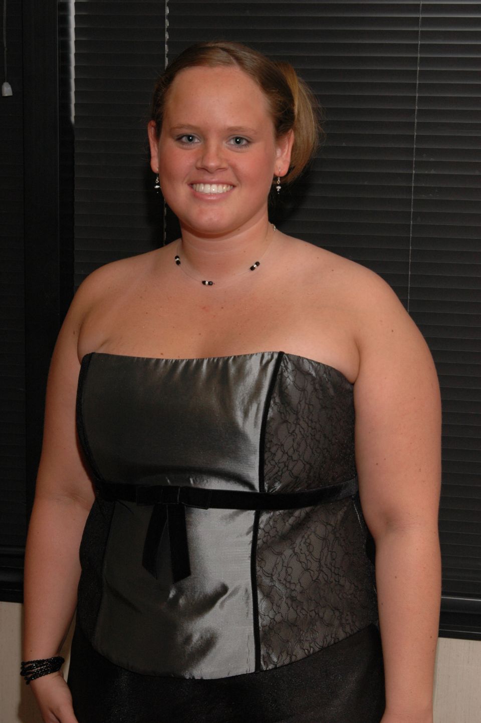 Woman in a strapless grey dress with black accents and jewelry
