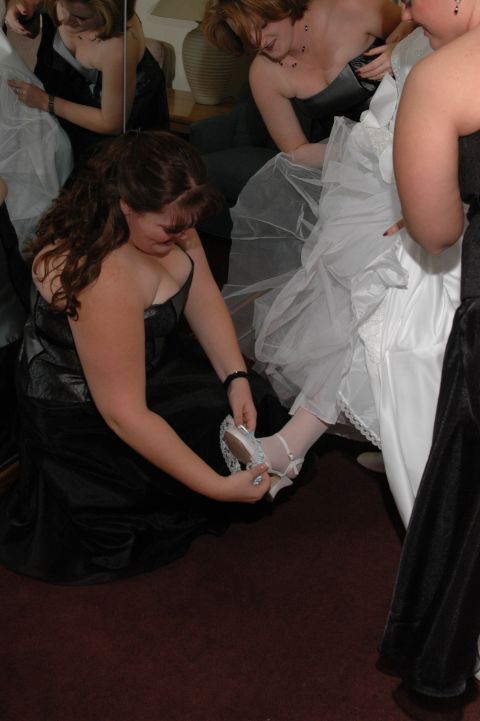 1985 Ford Crown Victoria LTD - A woman helps a bride put on her shoe before a wedding ceremony.