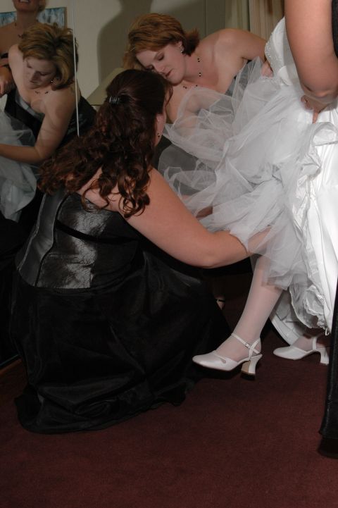 1985 Ford Crown Victoria LTD - A bride's wedding dress is being adjusted by attendants before the ceremony.