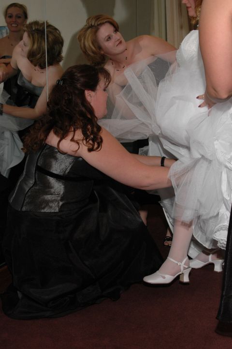 1985 Ford Crown Victoria LTD - A wedding party prepares, with one woman helping adjust the bride's dress.