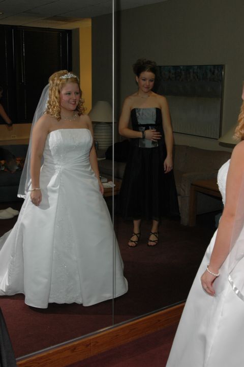 1985 Ford Crown Victoria LTD - A bride in a white wedding dress and a bridesmaid in a black dress are reflected in a large mirror.