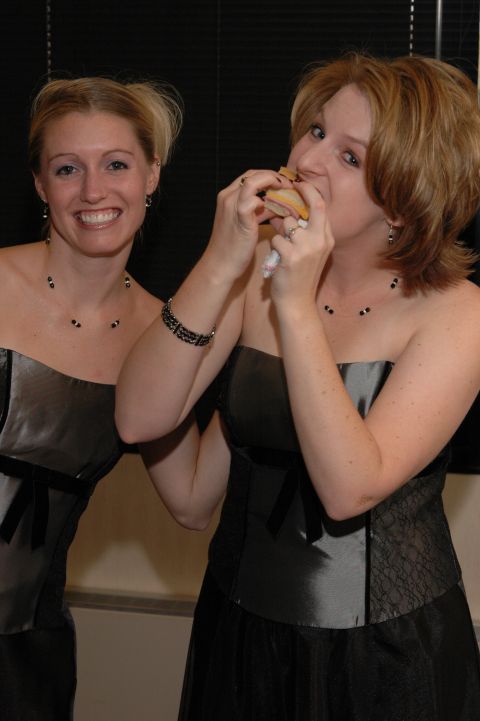 1985 Ford Crown Victoria LTD - Two women in formal dresses are seen at an event, one of them is eating a sandwich.