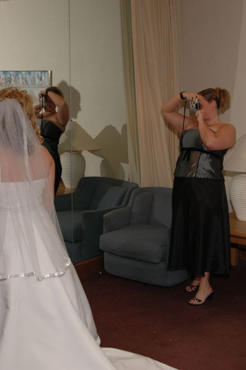 1985 Ford Crown Victoria LTD - A bridesmaid photographs a bride in a wedding dress in front of a mirror.