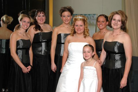 1985 Ford Crown Victoria LTD - A wedding party poses for a photo, with the bride in a white gown and bridesmaids in matching black dresses.