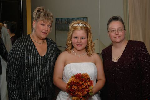 1985 Ford Crown Victoria LTD - A bride poses with two other women, likely family members, on her wedding day.