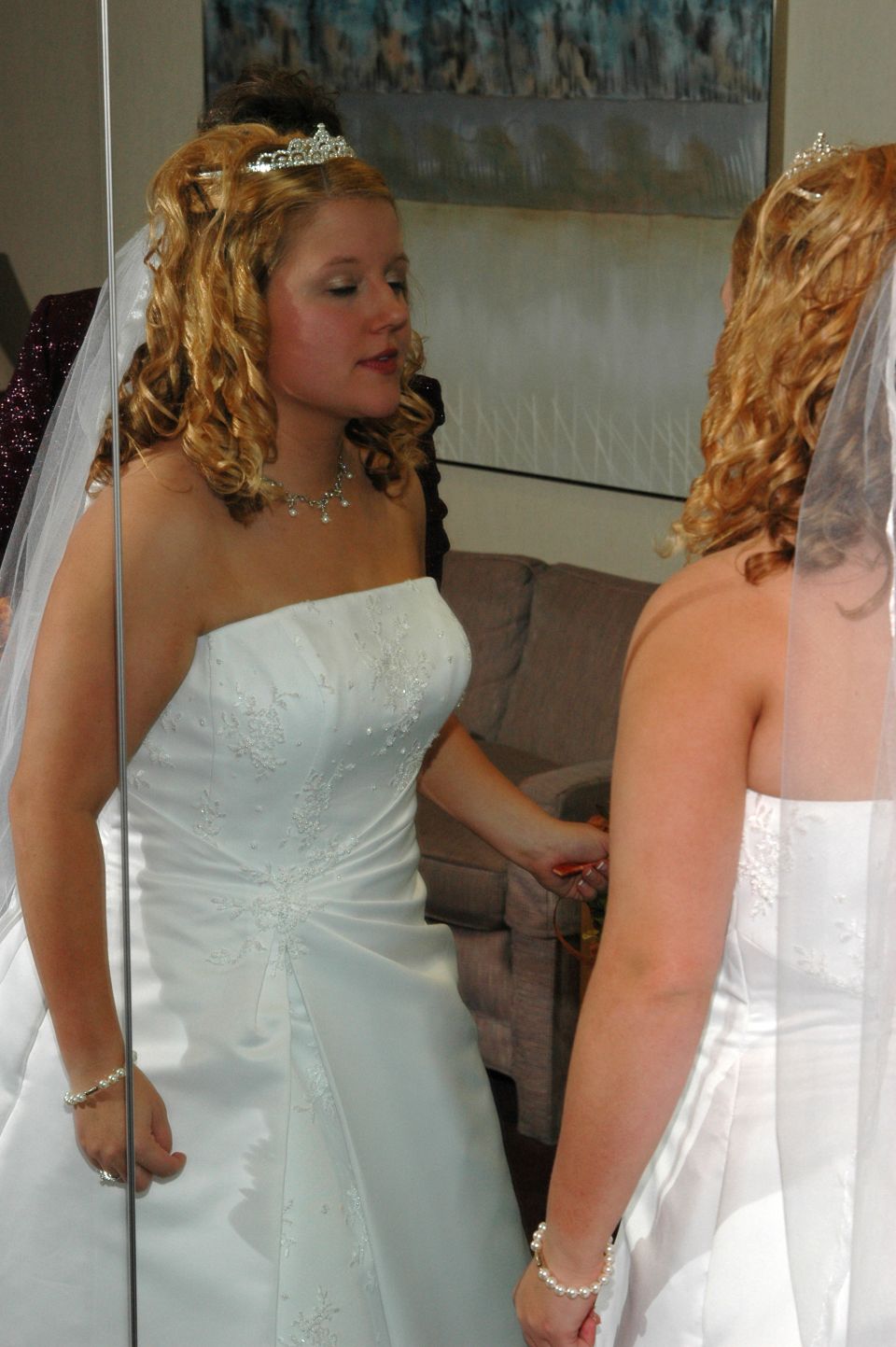 Bride in wedding dress and tiara looking at her reflection in a mirror
