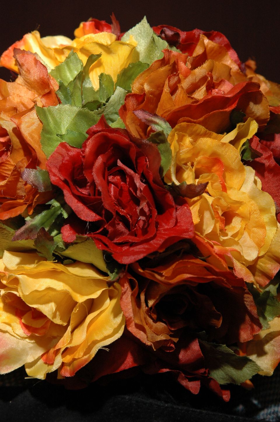 Close-up of a bouquet of artificial flowers in shades of red, orange, yellow, and green