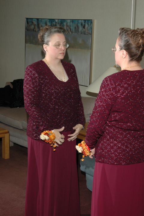 1985 Ford Crown Victoria LTD - A woman in a maroon dress with sparkling accents and corsages stands in front of a mirror.