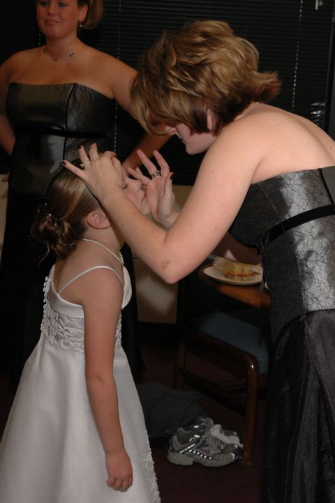 1985 Ford Crown Victoria LTD - A bridesmaid adjusts a flower girl's hair while another bridesmaid looks on.