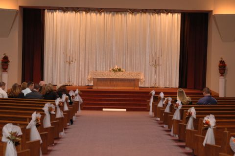1985 Ford Crown Victoria LTD - A wedding ceremony is set up in a church with decorated pews and an altar at the front.