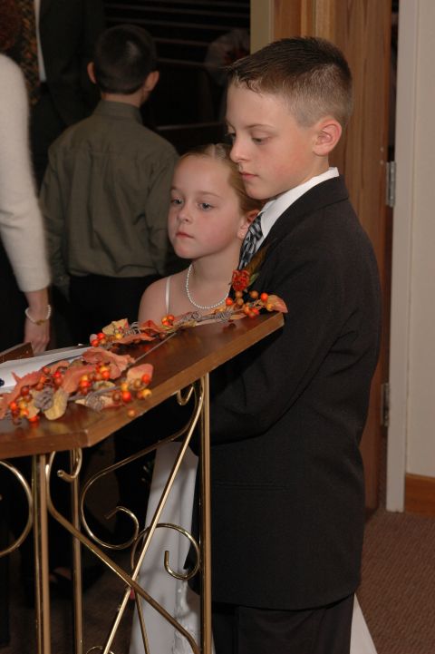 1985 Ford Crown Victoria LTD - Two children, dressed formally, stand attentively near a podium adorned with fall decorations.