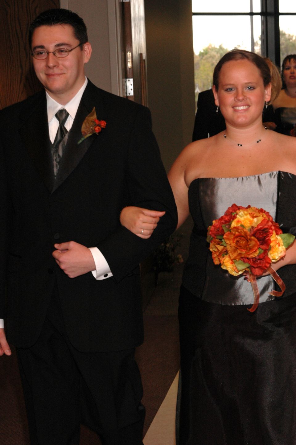 Groom and bride walking down aisle, groom in tuxedo, bride in strapless dress holding bouquet