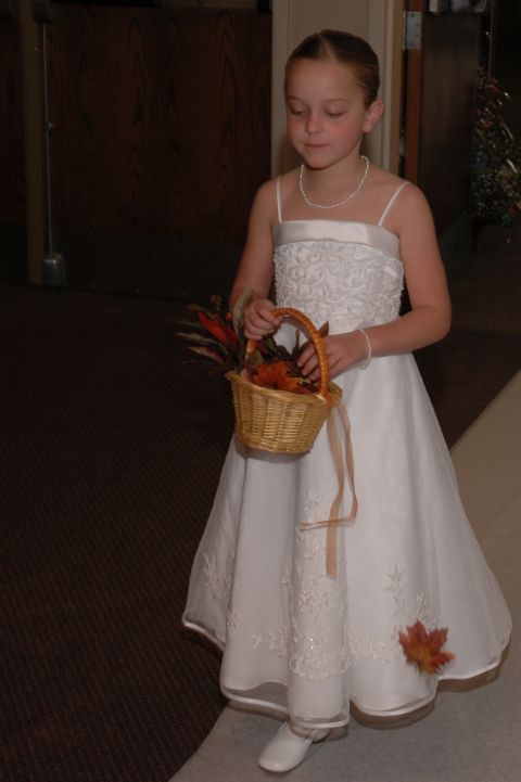 1985 Ford Crown Victoria LTD - A young flower girl walks down an aisle, holding a basket filled with decorative leaves.