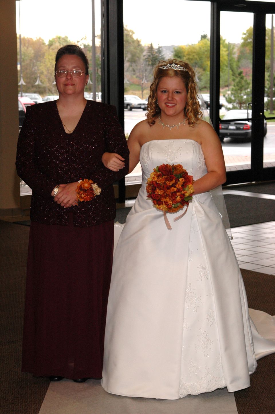 Bride in wedding dress and her mother walking arm-in-arm