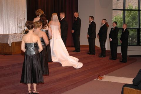 1985 Ford Crown Victoria LTD - A wedding ceremony is taking place with the wedding party lined up on raised steps.