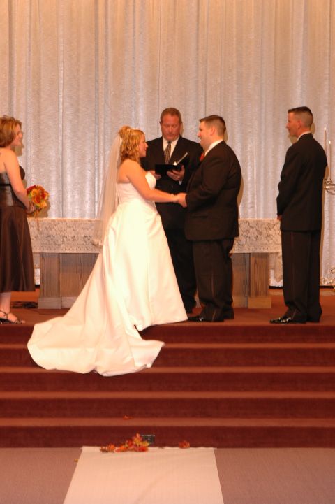 1985 Ford Crown Victoria LTD - A wedding ceremony takes place on a raised platform with a white curtain backdrop.