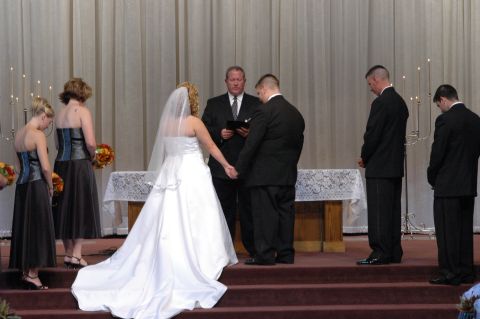 1985 Ford Crown Victoria LTD - A wedding ceremony is taking place with the bride and groom holding hands at the altar.