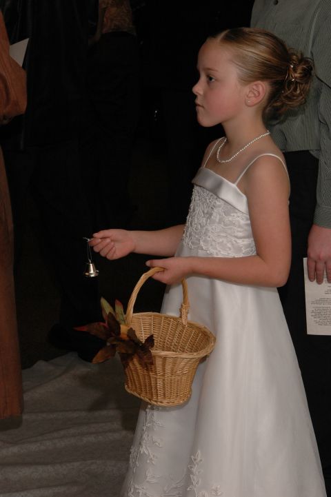 1985 Ford Crown Victoria LTD - A young girl in a formal white dress carries a basket, likely participating in a wedding ceremony.