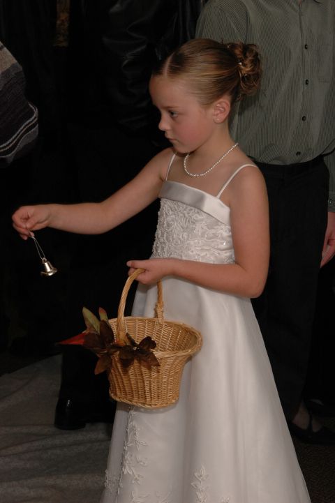 1985 Ford Crown Victoria LTD - A young flower girl in a formal white dress carries a basket, likely during a wedding ceremony.