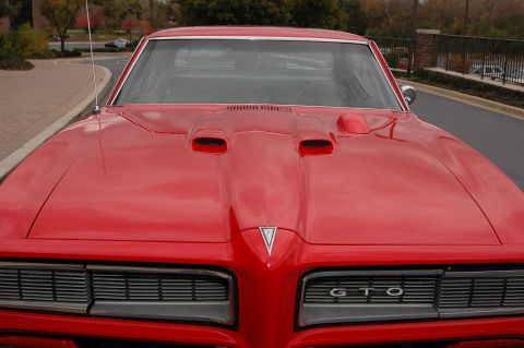 1985 Ford Crown Victoria LTD - Front view of a classic red Pontiac GTO, its iconic hood scoops and grille.